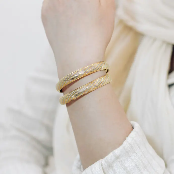 A woman wearing a white sweater and a gold bracelet